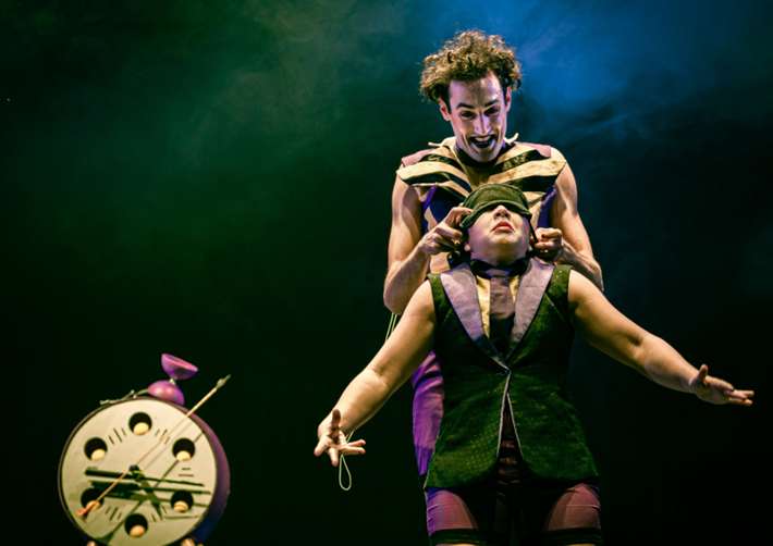 Two circus performers wearing green and purple costumes