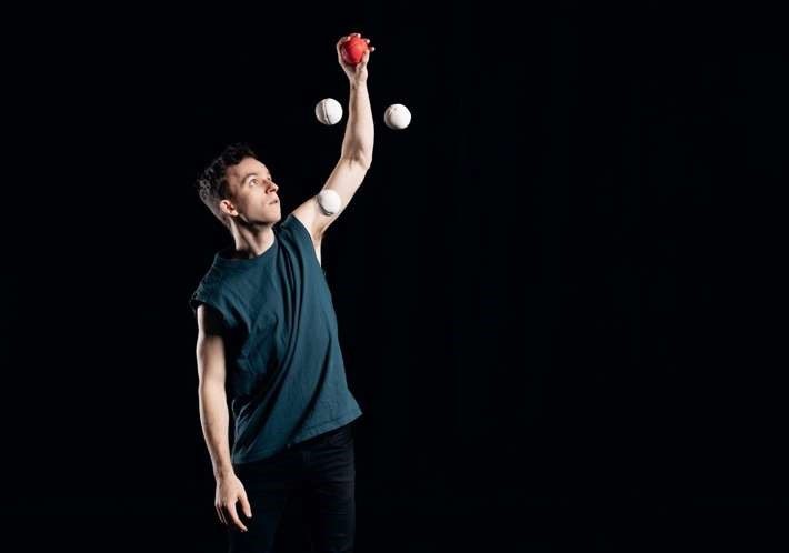 Mężczyzna w koszulce bez rękawów żongluje trzema piłkami